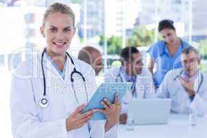 Smiling female doctor looking at clipboard while her colleagues