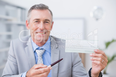 Smiling businessman holding cheque
