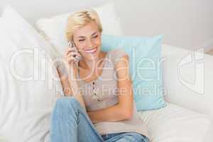 Smiling blonde woman phoning on the sofa