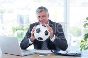 Smiling businessman holding soccer ball