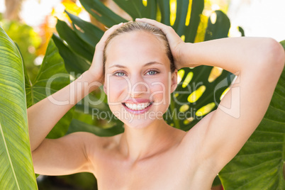 Beautiful blonde smiling at camera behind leaf