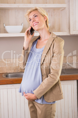 A smiling blonde pregnancy phoning