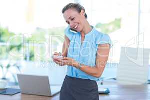 Smiling businesswoman having a phone call and taking notes