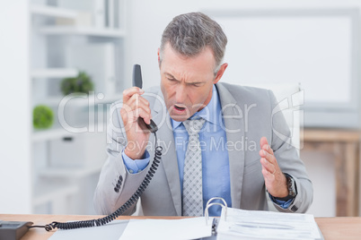 Irritated businessman answering phone