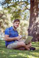 hipster using laptop and phone in the park