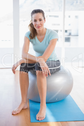 Woman looking at camera and sitting on exercise ball