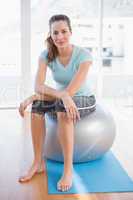 Woman looking at camera and sitting on exercise ball