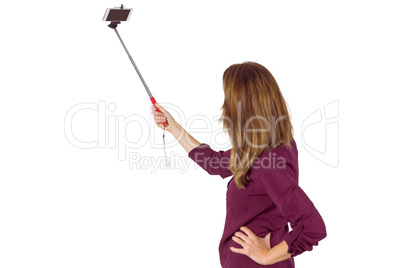 Wear view of pretty woman using a selfie stick