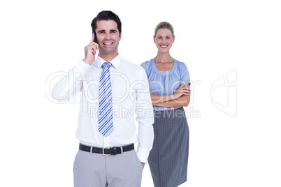 Businessman having phone call while his colleague posing