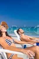 Happy couple relaxing on deck chair at the beach