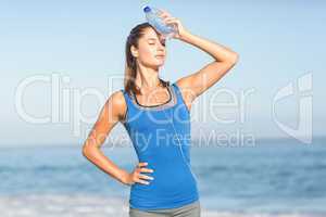 Beautiful fit woman putting water bottle in her head