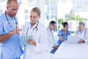 Two doctors looking at clipboard while their colleagues working