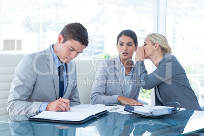 Businesswoman whispering something to her colleague