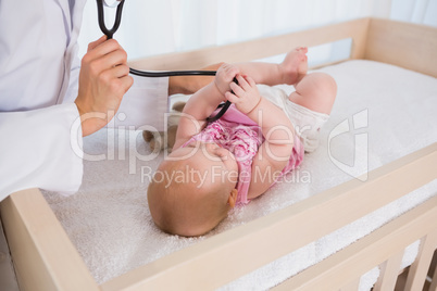 Beautiful cute baby girl with doctor using stethoscope