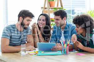 Happy creative business team using tablet in meeting