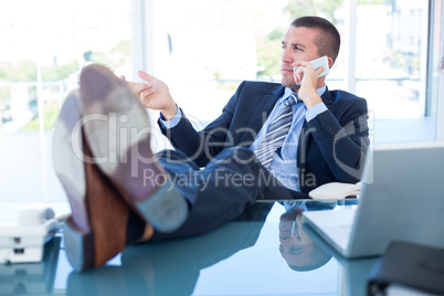 Businessman relaxing in a swivel chair and having a phone call