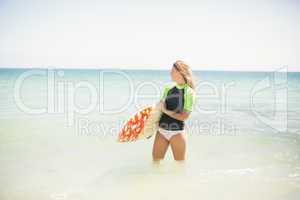 Pretty blonde woman holding surf board into the water