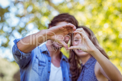 Cute couple in the park making heart shape