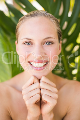 Beautiful blonde smiling at camera behind leaf