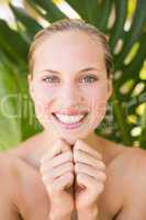 Beautiful blonde smiling at camera behind leaf