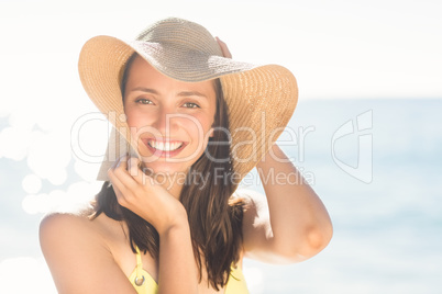 Brunette relaxing with a straw hat smiling at camera