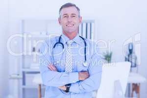 Happy male doctor looking at camera with arms crossed