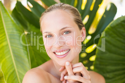 Beautiful blonde smiling at camera behind leaf