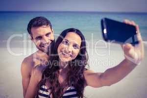 Happy couple taking a selfie at the beach