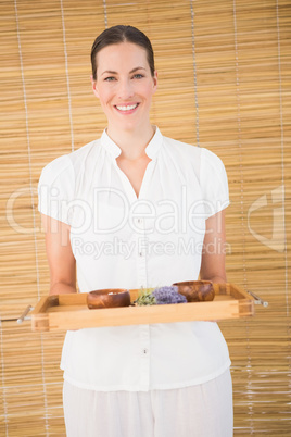 Smiling beauty therapist holding tray of beauty treatments
