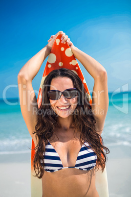 Pretty brunette with a surfboard looking at camera