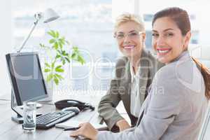 Smiling businesswomen looking at camera and working together