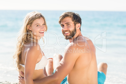 Happy couple relaxing together in the sand