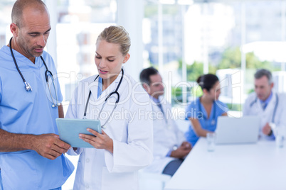 Two doctors holding clipboard while their colleagues working