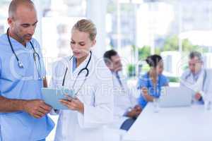 Two doctors holding clipboard while their colleagues working