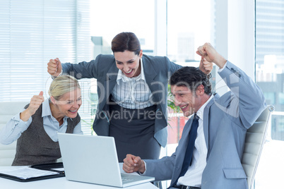 Business people cheering in front of laptop at office