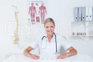 Doctor sitting at her desk smiling at camera