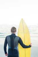 Man in wetsuit with a surfboard on a sunny day