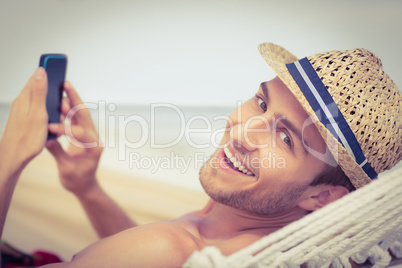 Handsome man texting on the hammock