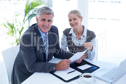 Smiling businessman with secretary checking file