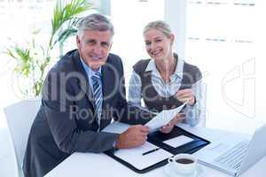 Smiling businessman with secretary checking file