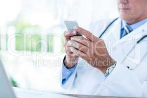 Doctor sitting at his desk and texting