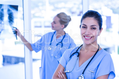 Happy doctor looking at camera while her colleagues looks at Xra