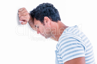 Sad man leaning his head against a wall