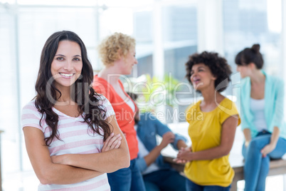 Smiling businesswoman with colleagues in background at office