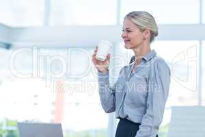 Smiling businesswoman holding disposable cup