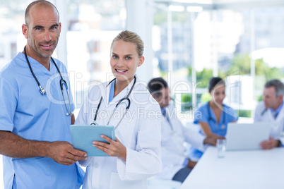 Two doctors holding clipboard while their colleagues working