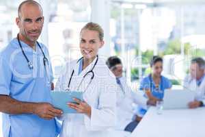 Two doctors holding clipboard while their colleagues working