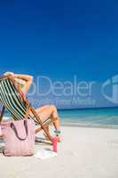 Side view of pretty brunette relaxing on deck chair at the beach