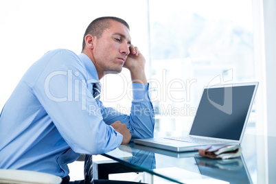 Tired businessman looking at his laptop