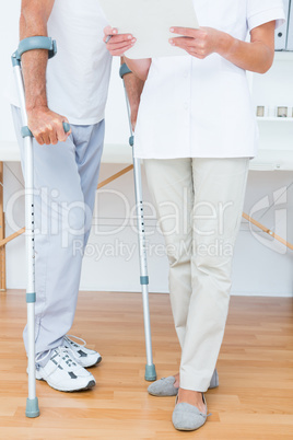 Doctor showing clipboard to her patient with crutch